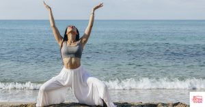 Woman on beach in the yoga goddess pose.