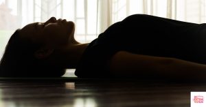 Woman meditating while lying down on floor. This article shares a 5 minute reset meditation.