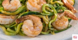 Whole30 shrimp scampi with zucchini noodles on a white plate.