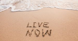 Live now drawn in sand on beach. How to practice mindfulness in daily life.