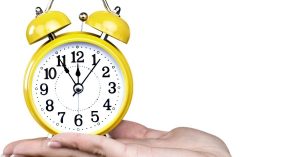 Person holding a yellow alarm clock. This post discusses the Pomodoro Technique pros and cons.