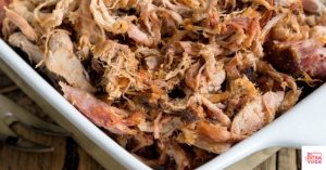 Paleo pulled pork in a white dish that was made in a slow cooker.