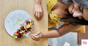 Woman eating a wrap with healthy ingredients. This article discusses mindful eating vs intuitive eating.