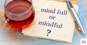 Napkin next to tea and a pen that says "mind full or mindful?" This article shares an excellent mindful eating worksheet.