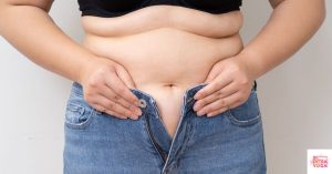 Woman trying to, but unable to, button her jeans. This article asks the question what does hormonal weight gain look like.