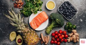Healthy foods including fruits, vegetables, proteins, and nuts laying on a black countertop. This article discusses the best anti-inflammatory hormone balancing diet plan.