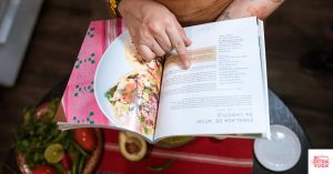 Person holding a cookbook and reading it. This article discusses the best books for an anti-inflammatory diet.