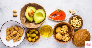 Aerial view of salmon, nuts, olive oil, coconut, and avocado on a counter. This article share a free healthy gut diet plan pdf.