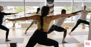 People practicing yoga during class in front of windows. This article discusses vinyasa yoga benefits.