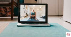 Laptop with yoga on the screen set on the floor on top of a yoga mat. This article asks "can you teach yourself yoga"?