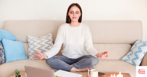 Woman sitting on couch at home with work on table and meditating. This article shares some 10 minute meditations.