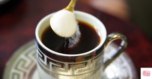 Sugar on a spoon being poured into coffee. This article shares a list of foods that cause inflammation.