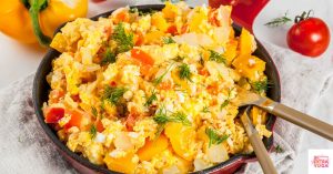 Scrambled eggs in a skillet with red peppers mixed in. This article shares a Paleo egg scramble recipe.