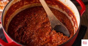 Bolognese sauce in a Dutch oven pot on the stove. This article shares a recipe for Whole30 Bolognese.