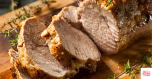Cooked pork tenderloin on a wooden cutting board. This is a recipe for Whole30 pork tenderloin.