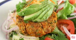 Tuna patty with avocado on top over a bed of greens. This recipe is for paleo tuna patties.