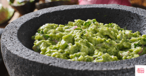 Guacamole in a gray bowl. This article shares a paleo guacamole recipe.